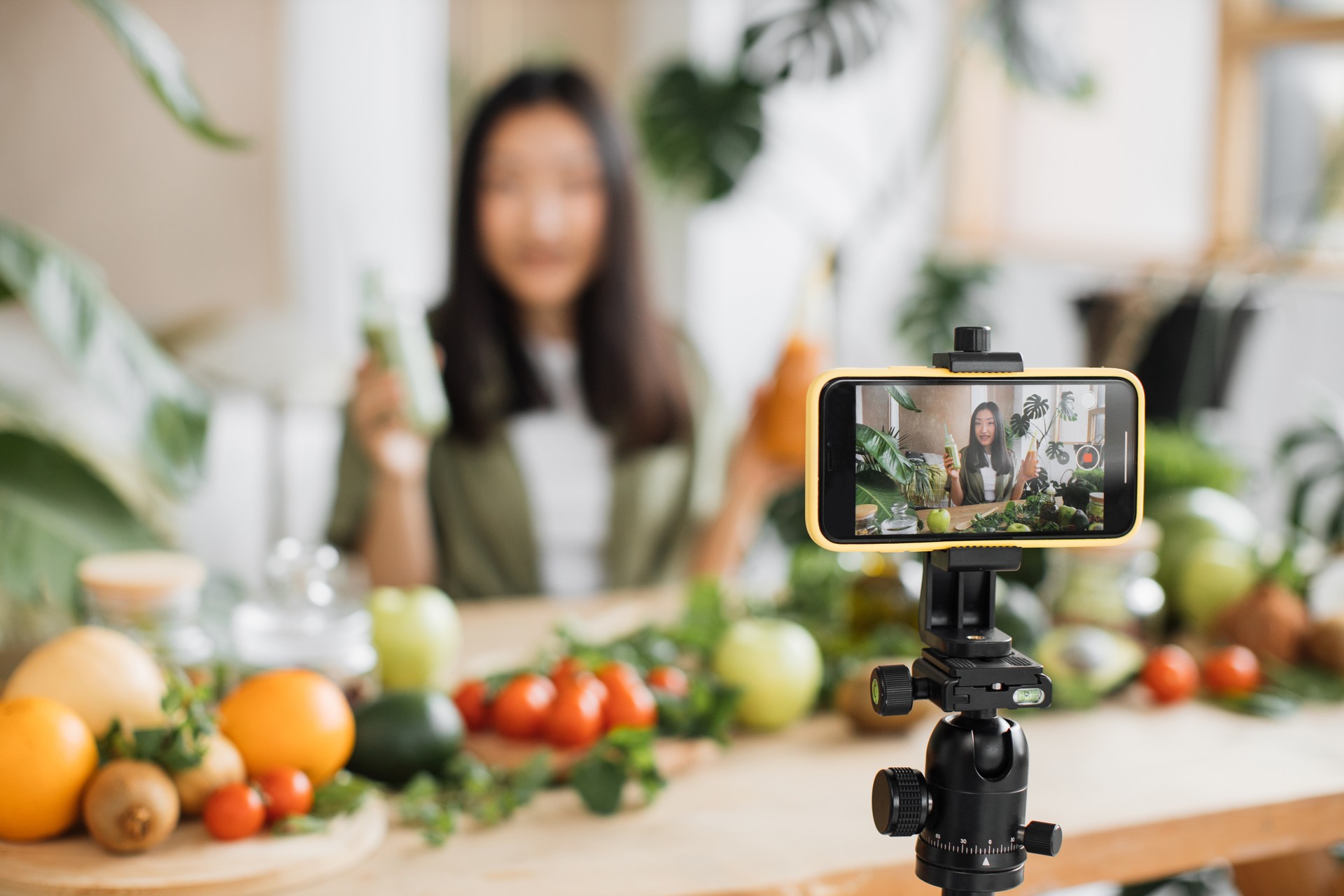 Asian woman making healthy food using phone creating video content for social media