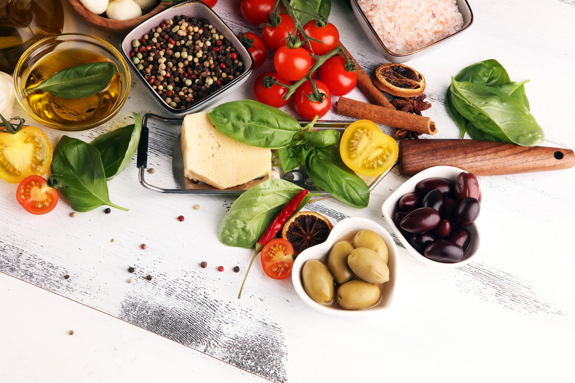 Italian food background with herbs and spices, vine tomatoes, basil, spaghetti, olives, parmesan, olive oil, garlic, peppercorns and fresh rosemary